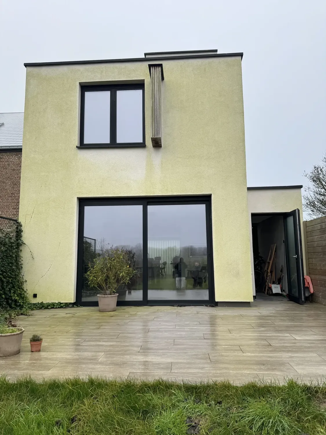 Witte crepi woning voor reiniging groene aanslag Kortrijk